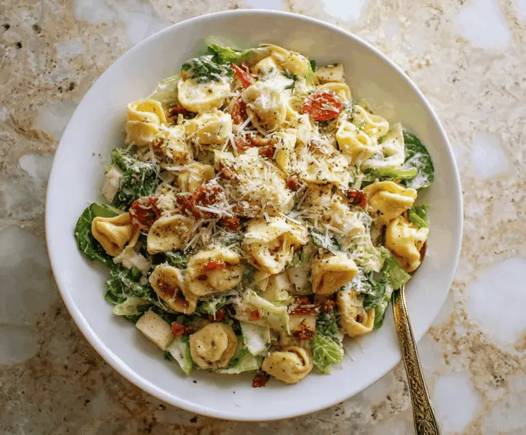 Creamy cheese tortellini Caesar pasta salad with fresh romaine lettuce, grated Parmesan, and crunchy croutons in a vibrant, appetizing dish