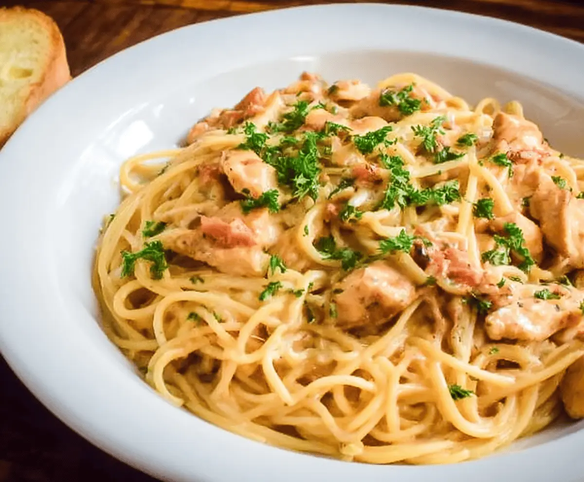 Delicious chicken spaghetti served on a plate with melted cheese and herbs, perfect for a comforting meal.