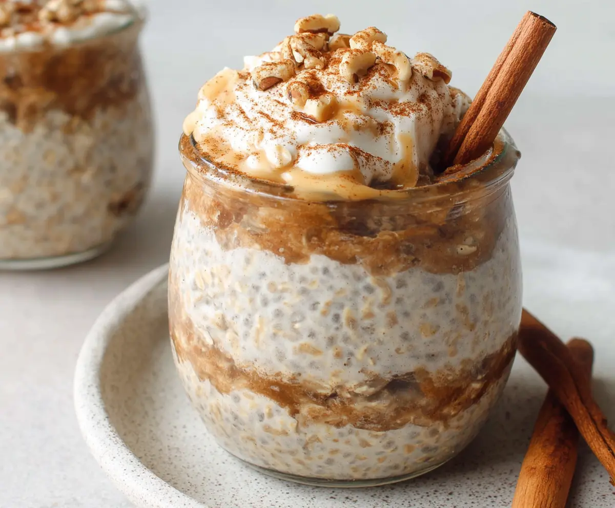 Creamy cinnamon roll overnight oats in a clear jar with swirls of cinnamon and icing topping for a quick, delicious breakfast.