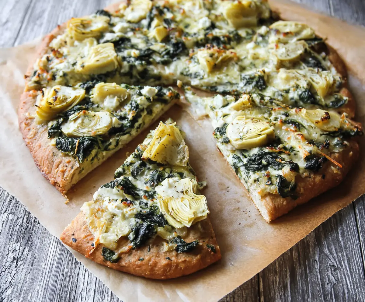 Delicious high protein spinach and artichoke pizza topped with fresh greens and melted cheese.