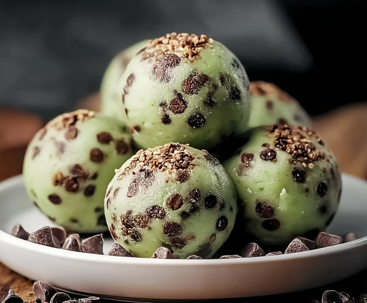 Delicious Mint Chocolate Chip Protein Balls on a white plate, garnished with fresh mint leaves, perfect for a healthy snack.