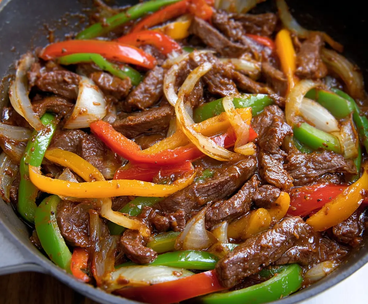 Delicious pepper steak with colorful bell peppers and onions on a plate.