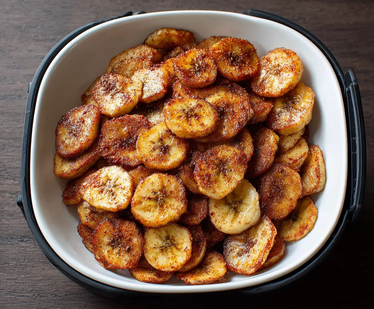 Crispy air fryer cinnamon banana chips on a plate, garnished with cinnamon for a healthy snack.