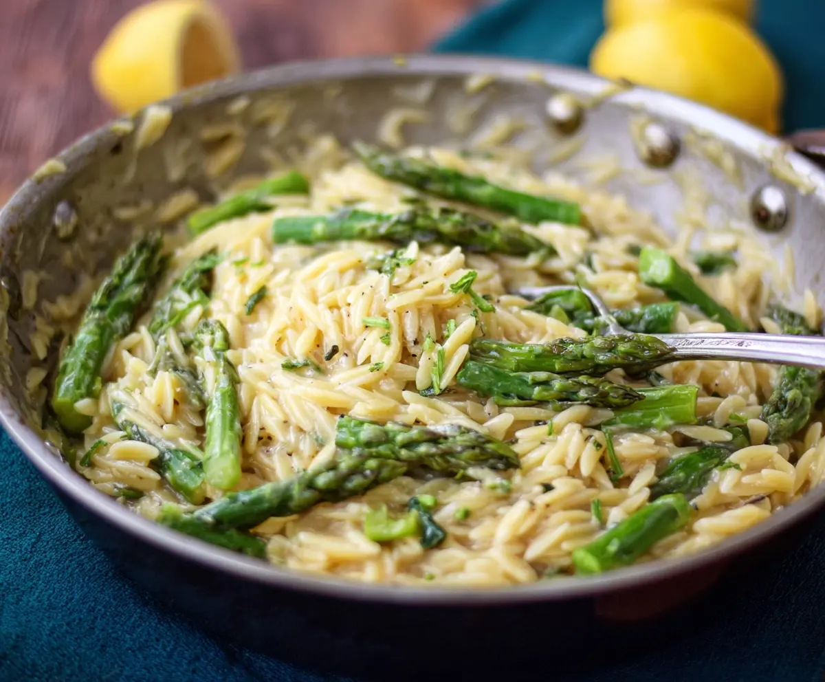 Creamy lemon garlic orzo with fresh asparagus on a plate, garnished with herbs, for a delicious vegetarian meal.