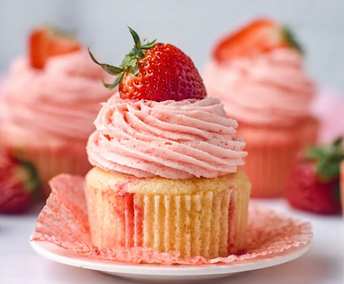 Delicious homemade strawberry cupcakes topped with fresh strawberries and whipped cream.