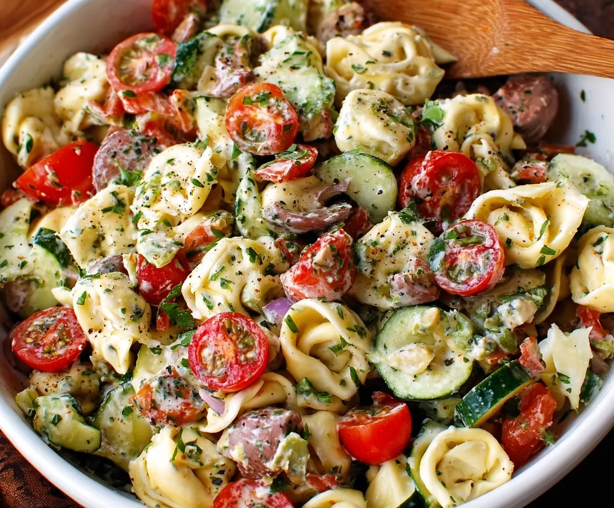 Colorful tortellini pasta salad with fresh vegetables and herbs, perfect for summer gatherings.